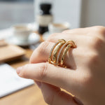 Hand wearing a gold ring with a blurred coffee shop background