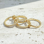stackable gold hoop rings on a light stone surface