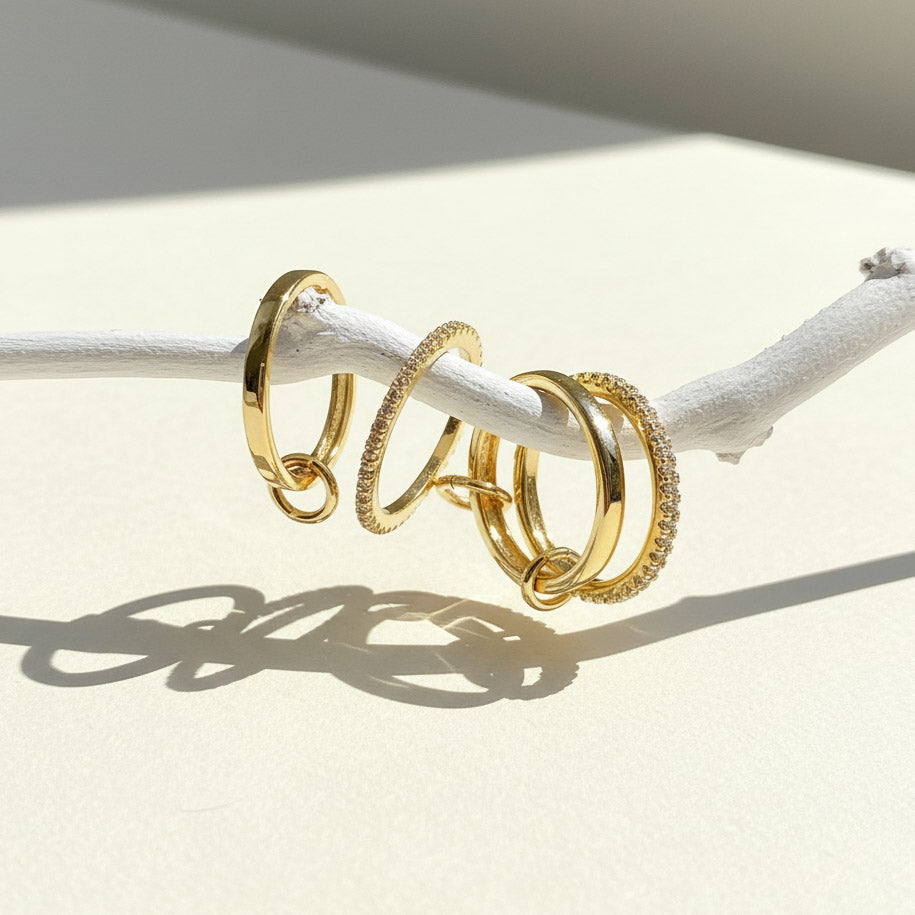 stackable gold rings on a white branch with a neutral background