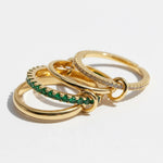 Three gold rings with green gemstones on a white background