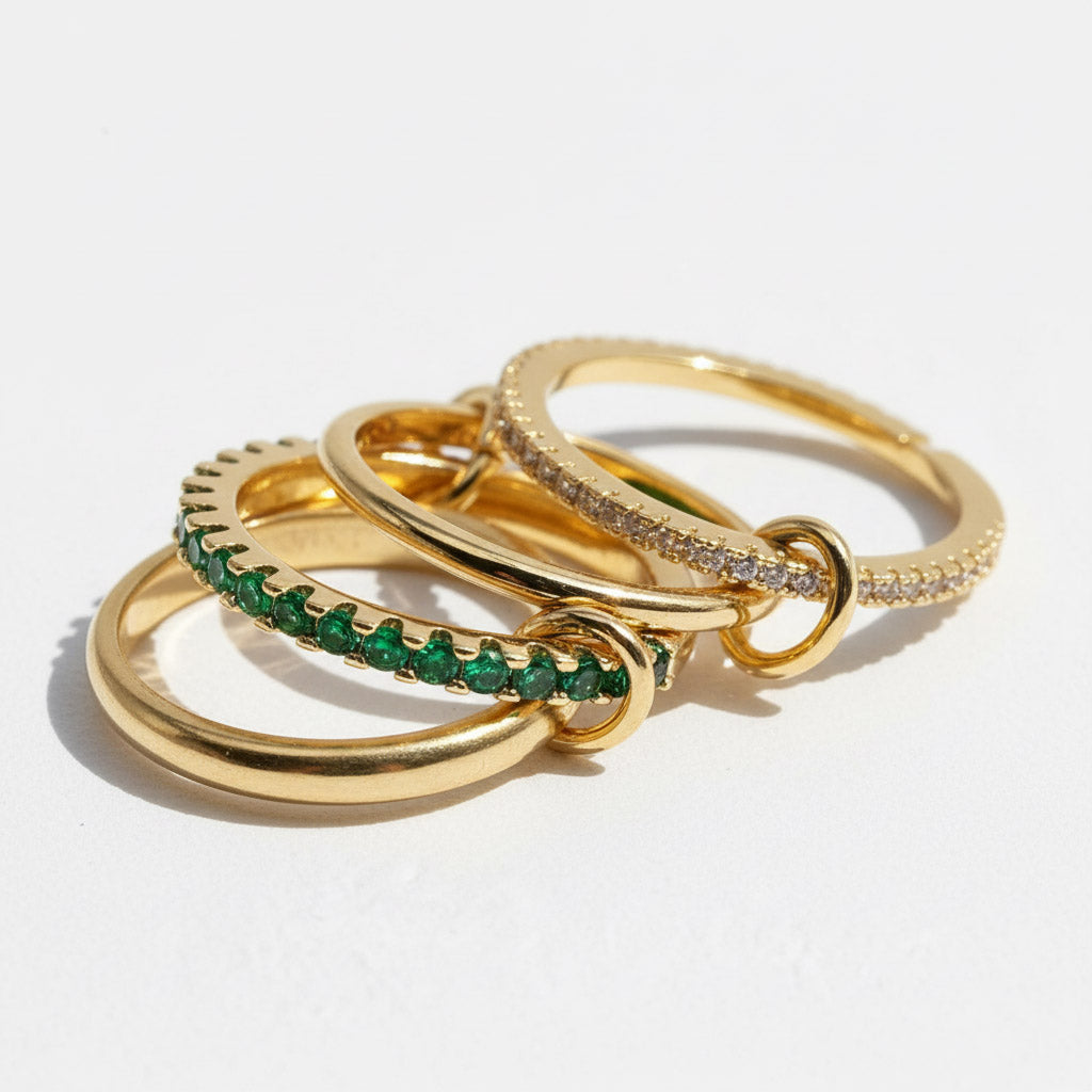 Three gold rings with green gemstones on a white background
