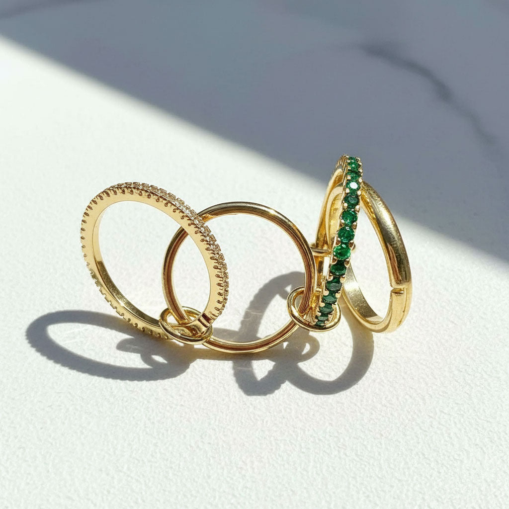 Three gold rings with green gemstones on a white surface