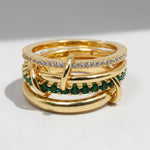 Gold ring with green gemstones on a white background