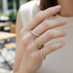 Close-up of a hand wearing two rings with a blurred outdoor background
