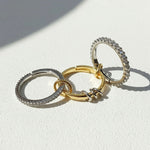 Three rings in gold, silver, and rose gold on a light background