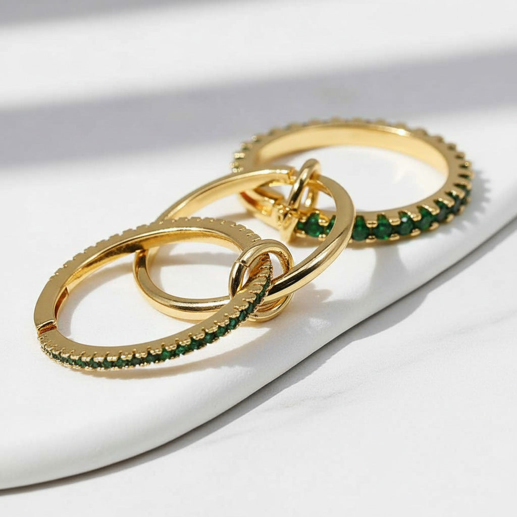 Gold rings with green gemstones on a white surface