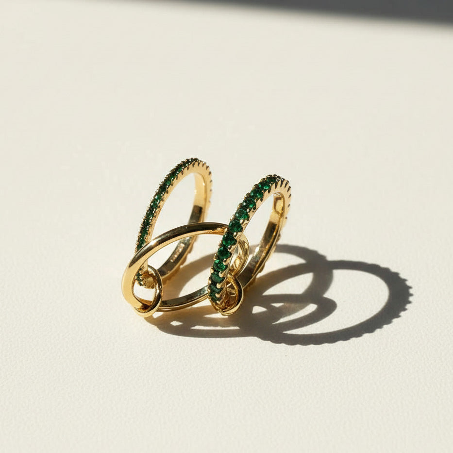 Gold ring with green gemstones on a light beige background