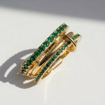 Gold ring with green gemstones on a white background