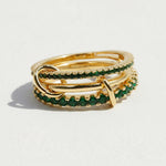 Gold and emerald green ring on a light gray background