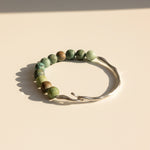 Matte African Turquoise Jasper bracelet with stainless steel hook on cream background in warm sunlight