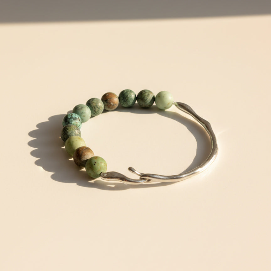 Matte African Turquoise Jasper bracelet with stainless steel hook on cream background in warm sunlight