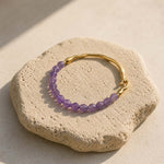 Amethyst and gold hook bracelet styled on natural beige stone slab