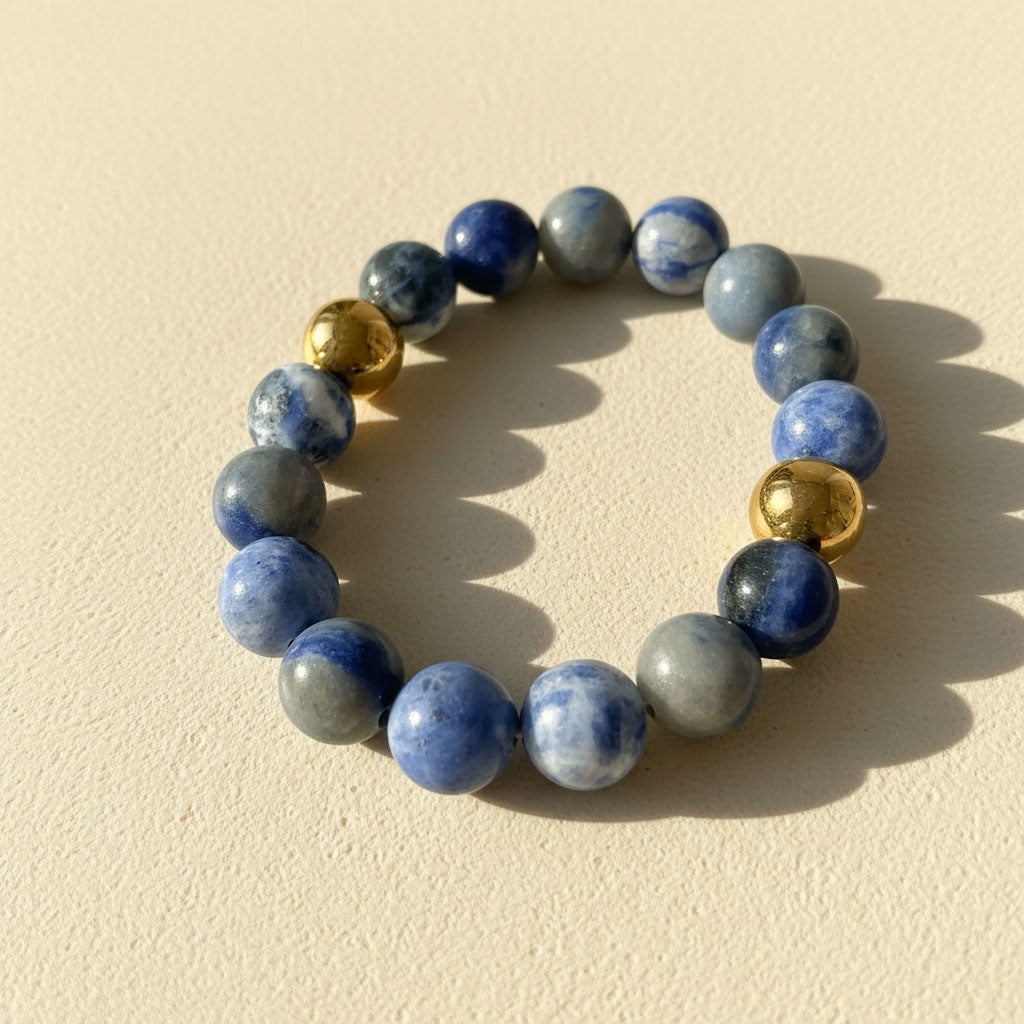 Blue Aventurine gemstone bracelet with gold stainless steel beads on cream background in warm sunlight