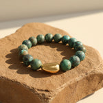 African Turquoise natural stone bracelet with gold accent bead on sandstone display