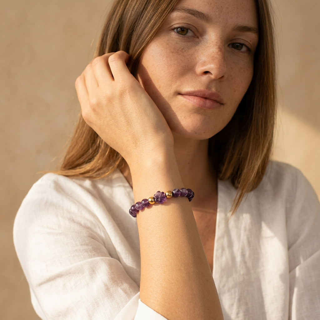 Amethyst gemstone bracelet with gold accents worn by female model in warm sunlight
