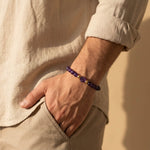 Amethyst gemstone bracelet worn by male model in relaxed natural sunlight