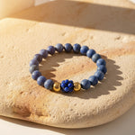 Matte sodalite gemstone bracelet with lapis lazuli center bead on a stone surface
