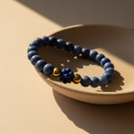 Blue sodalite bracelet with gold stainless steel accents on a beige surface