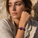 Woman wearing layered amethyst gemstone bracelets with gold details