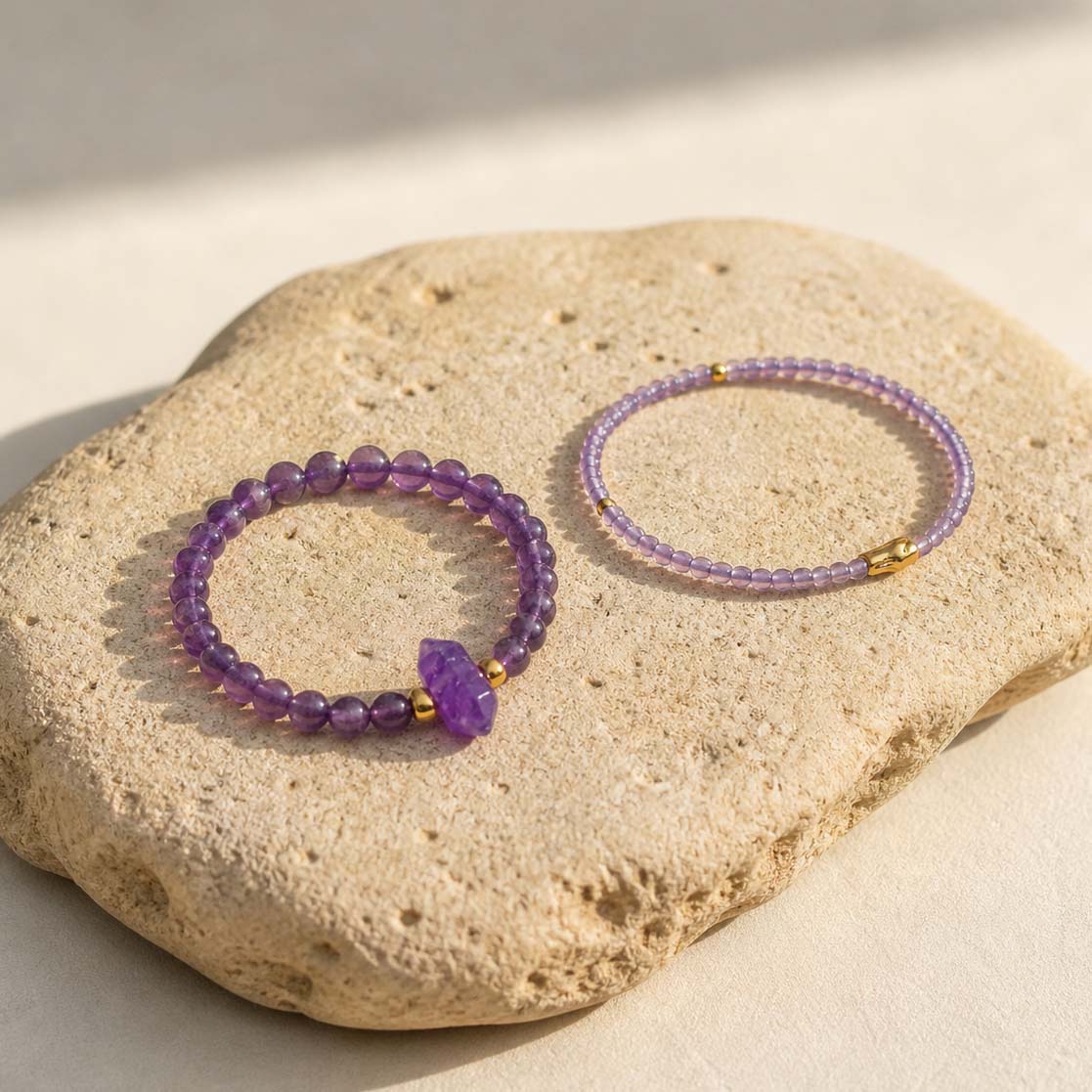 Amethyst bracelet stack styled on textured beige stone slab