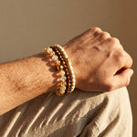 Tiger Eye Rutilated Quartz and camphor wood beaded bracelet worn on male wrist