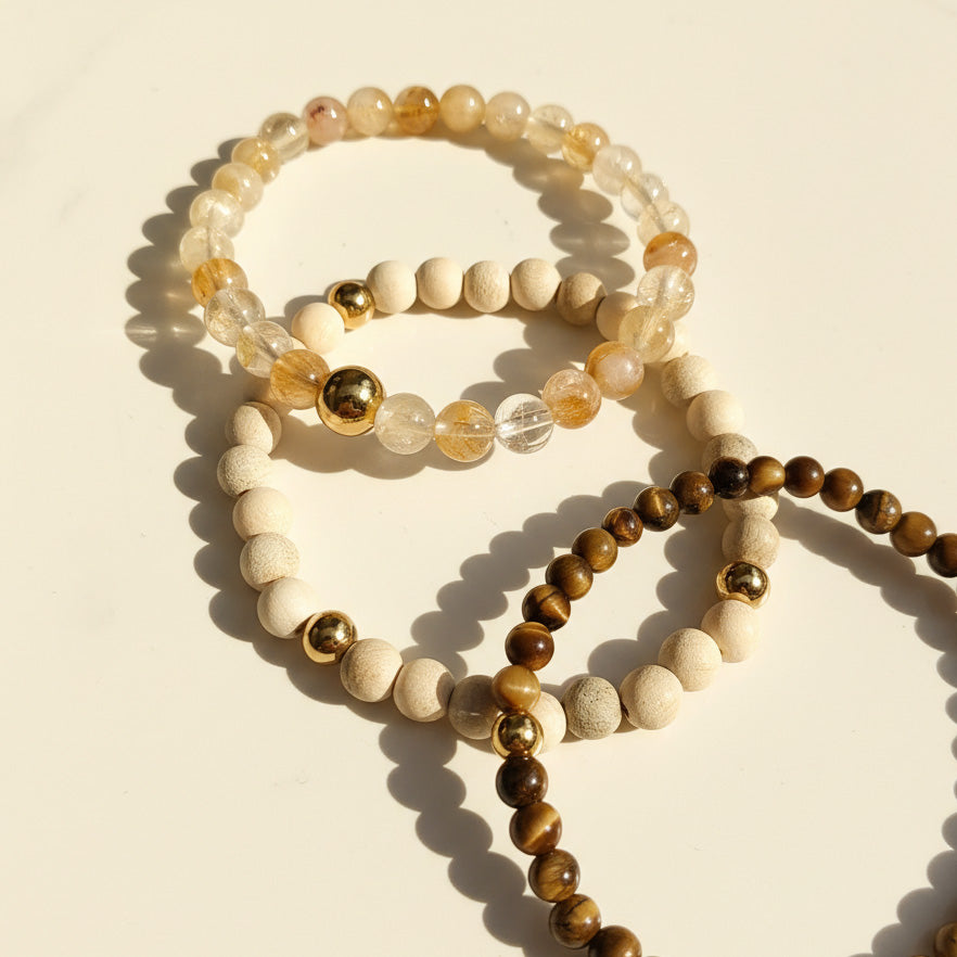 Natural gemstone bracelets Tiger Eye Rutilated Quartz and camphor wood on a beige background