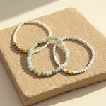 Amazonite and white turquoise gemstone bracelet set with pearl on natural stone background