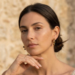 Woman wearing gold earrings with a blurred natural background