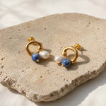 Sodalite and pearl drop earrings on natural stone surface