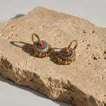 Enamel and green gemstone convertible hoop earrings on sunlit stone