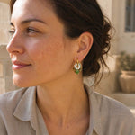 Woman wearing green garnet pearl convertible hoop earrings in natural light outdoors