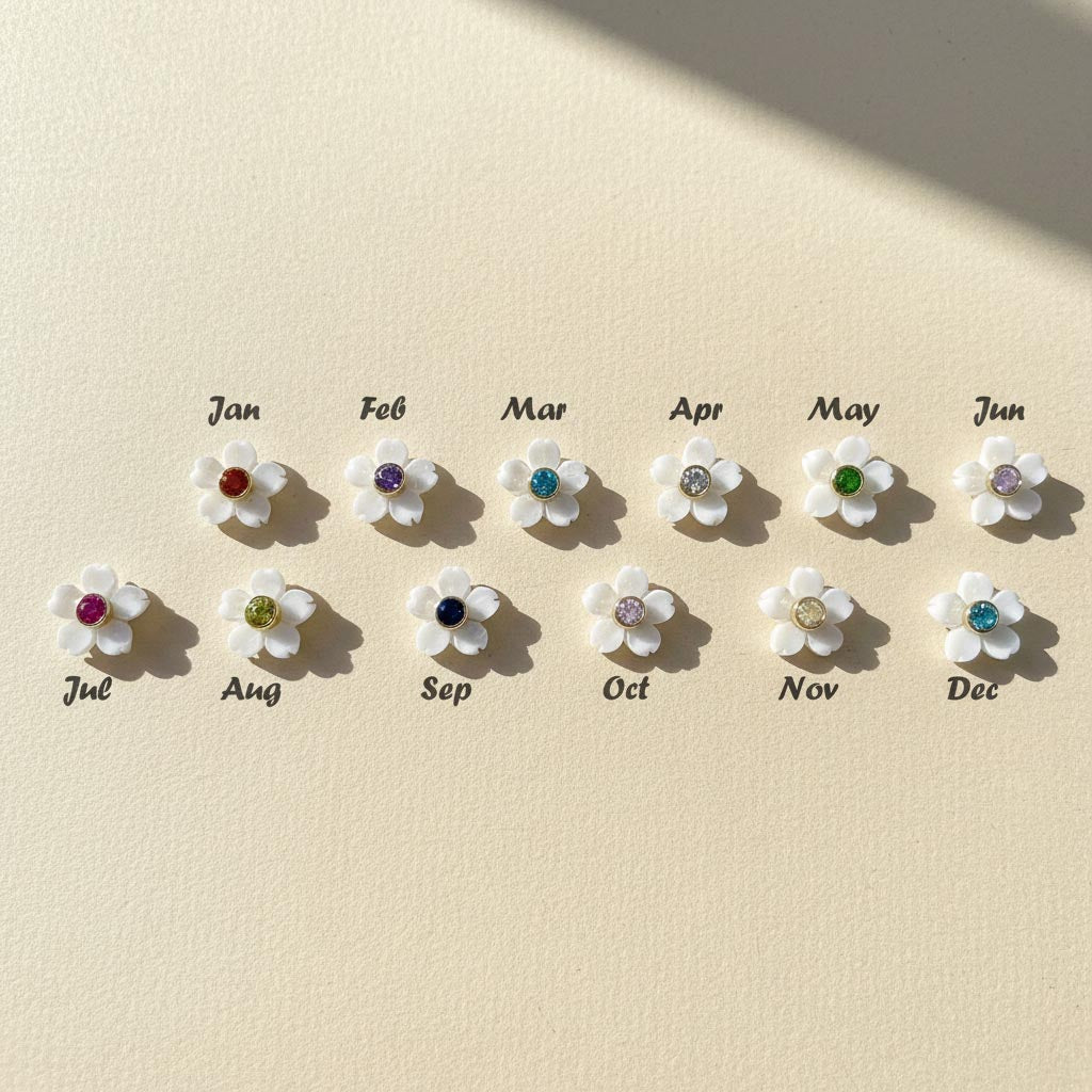 Set of twelve floral earrings with colored gemstones, each labeled for a month on a beige background.