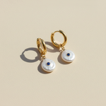 Gold hoop earrings with pearl drops on a beige background