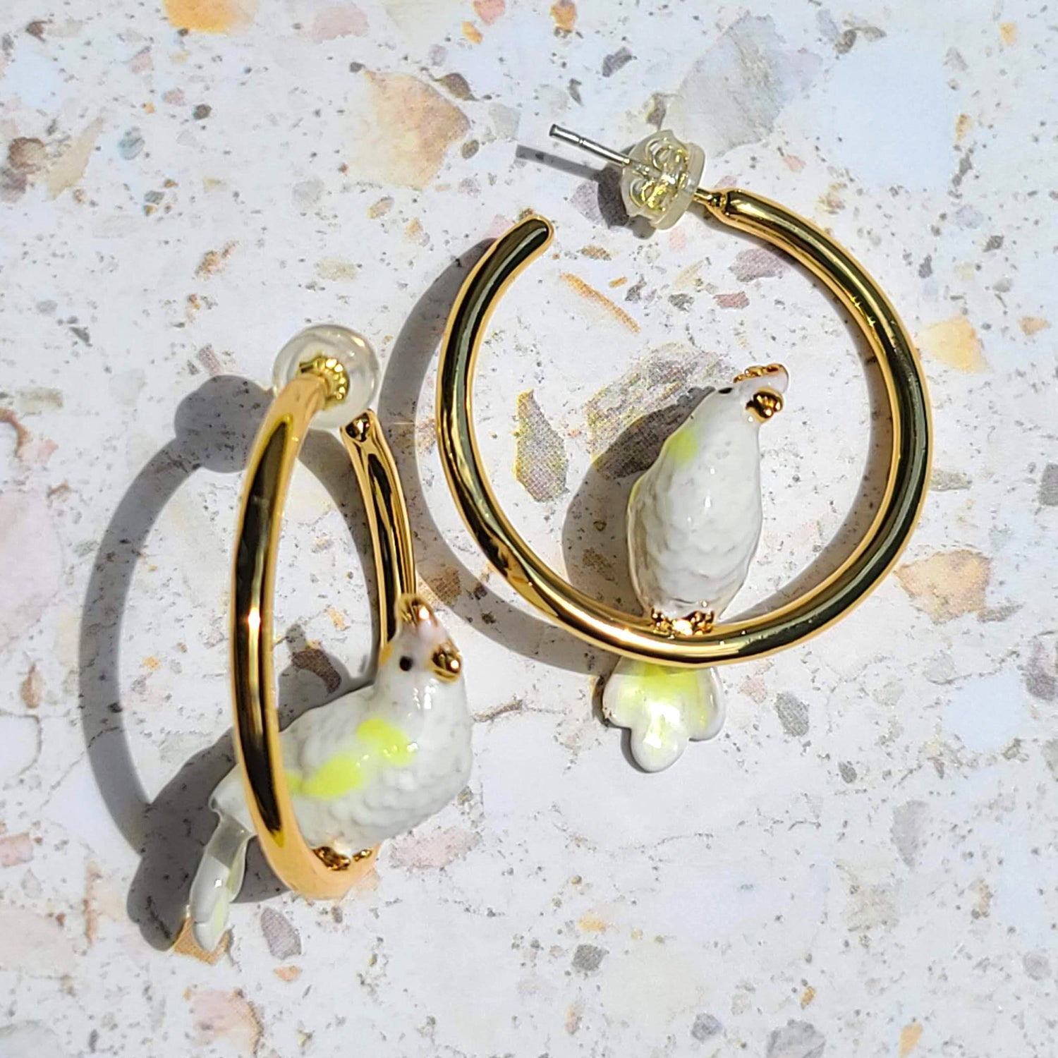 Gold-plated hoop earrings featuring charming white cockatoo bird details in enamel, perfect for adding playful elegance to your style